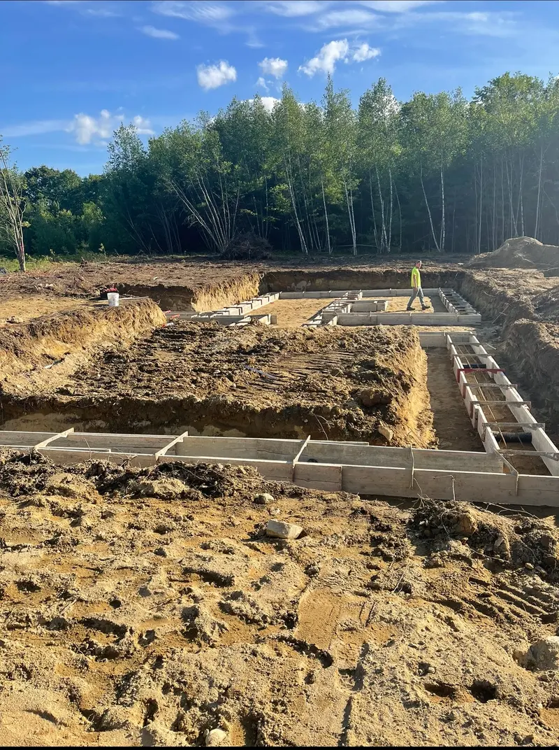 Footing forms set on a house lot with a crew member checking the layout