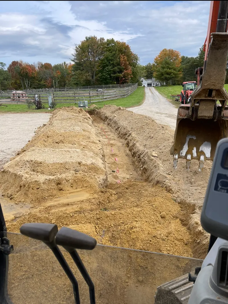 View from the cab of a Boynton Brook excavator digging a trench across a farm property in Saco, Maine