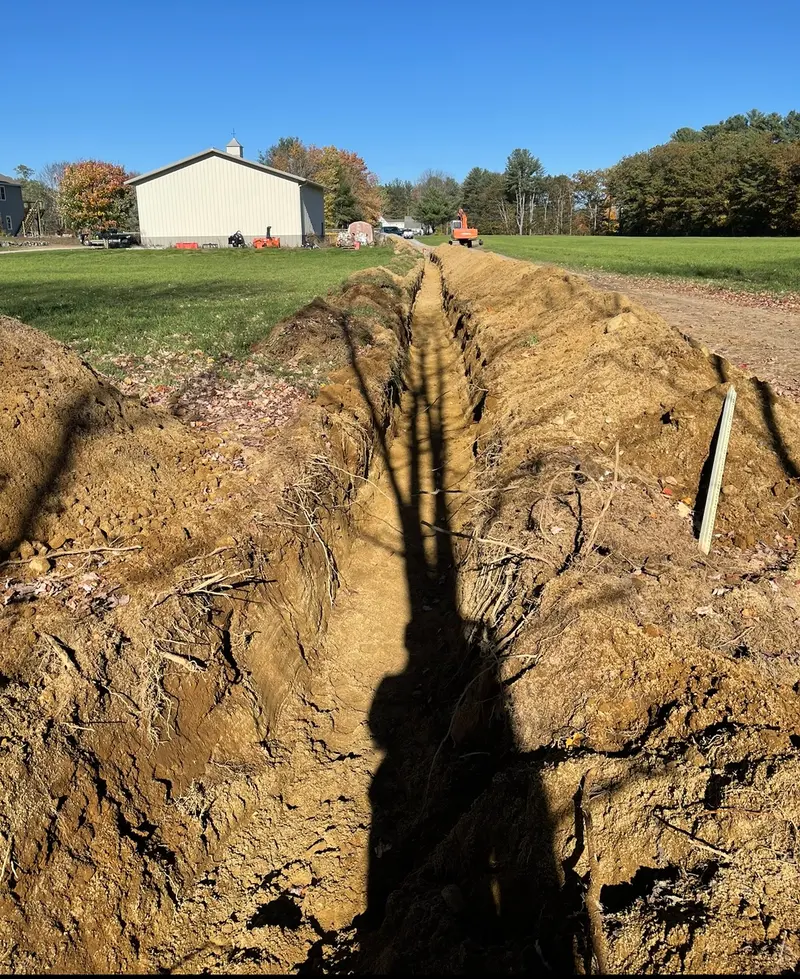 Utility trench dug across a farm property toward the road