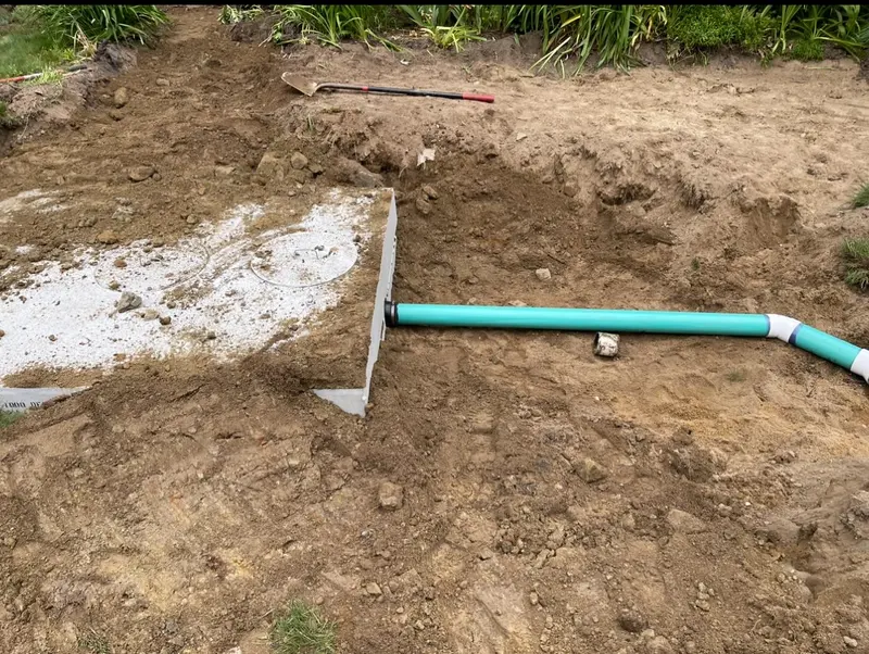 Concrete septic tank set in an open trench with the inlet pipe run to it