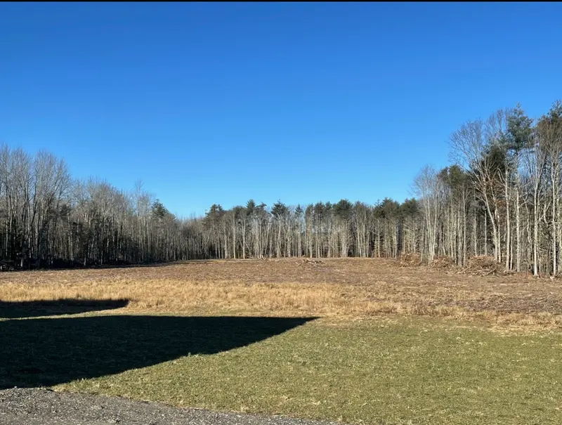 Cleared field under a clear blue winter sky, brush hauled and grade roughed in